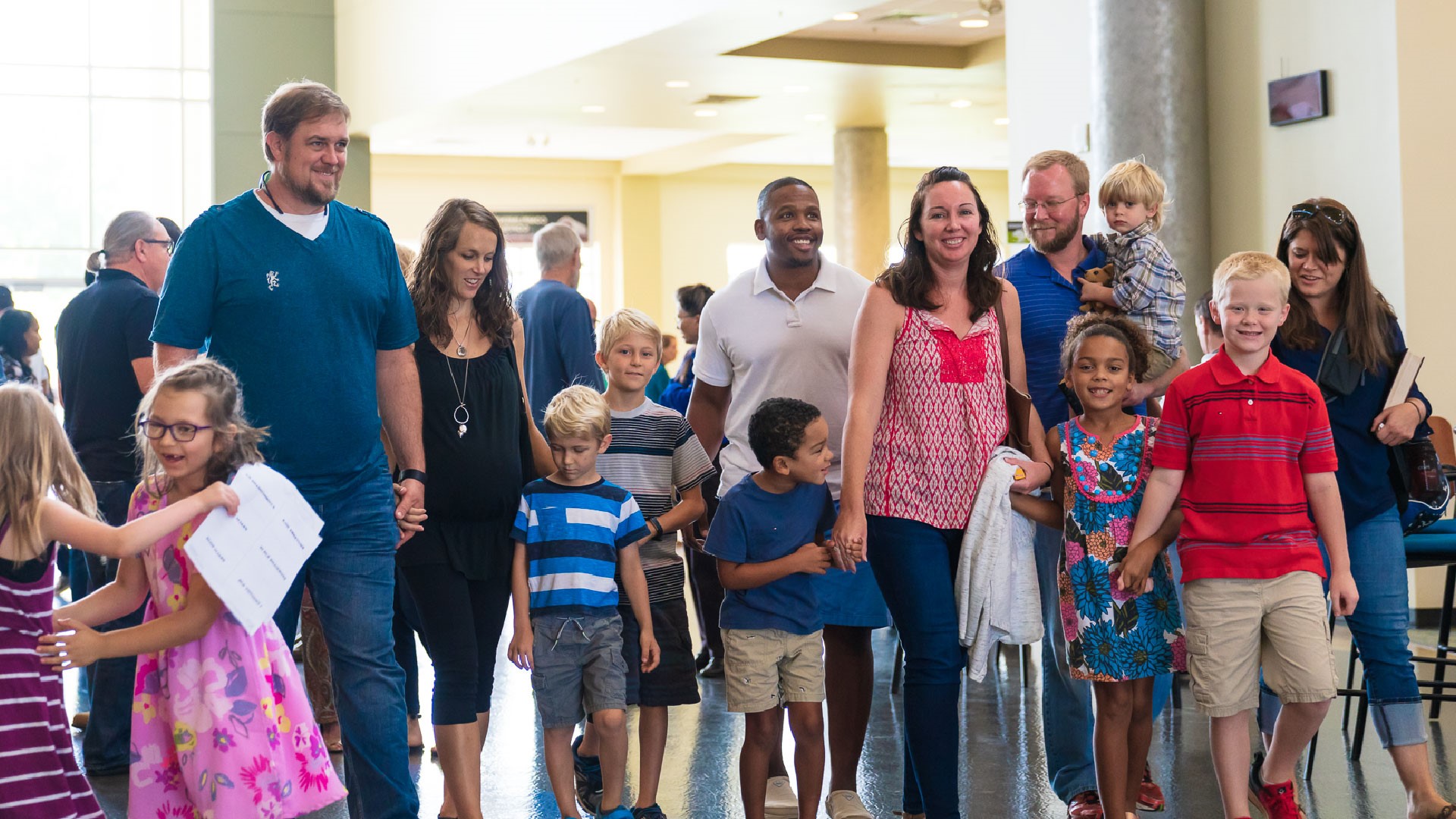 A group of parents each with their children walking out of the Brookwood Church auditorium